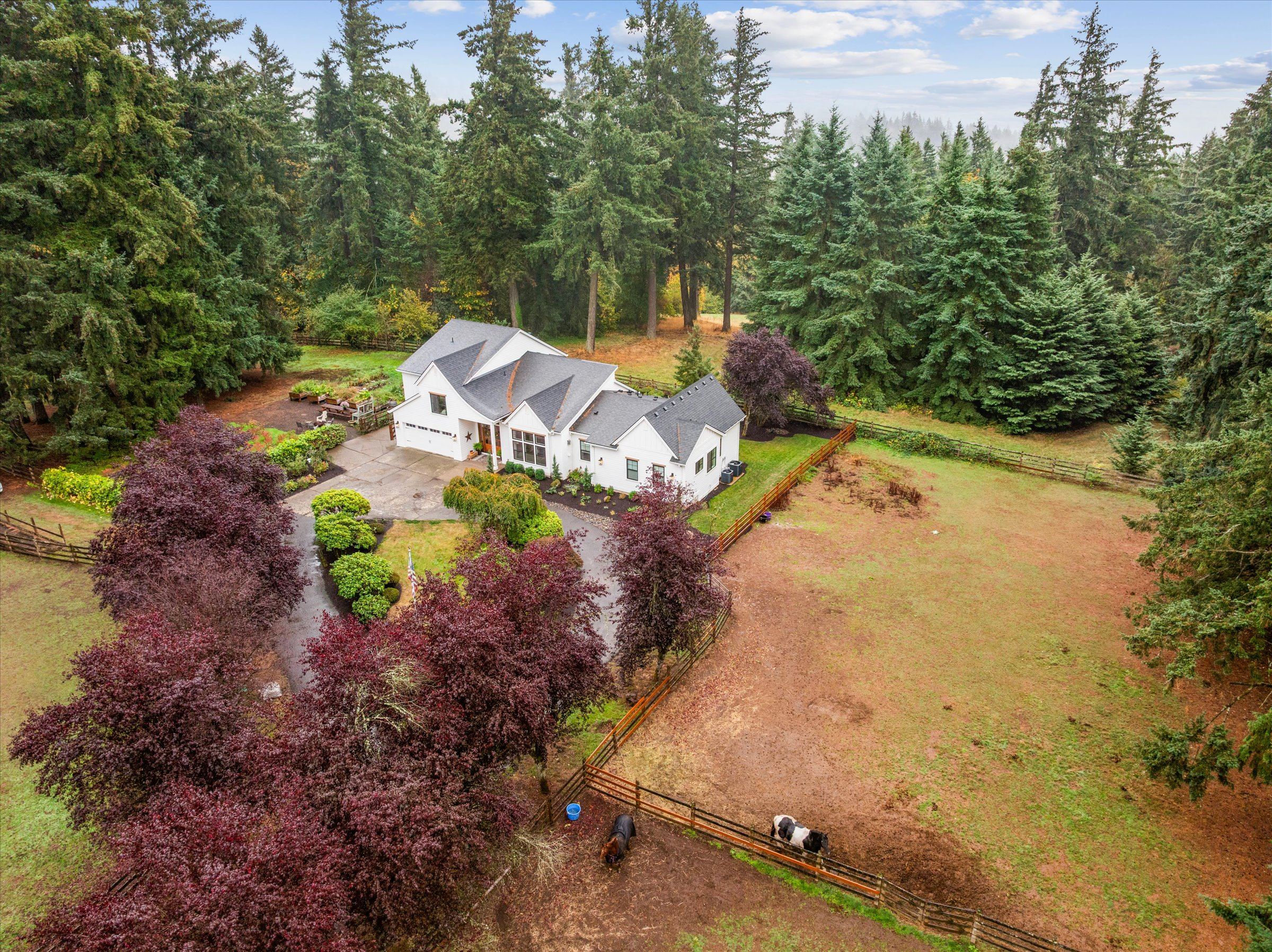 Aerial view of the white modern farmhouse, tree-lined drive, horse fencing, barns and paddocks on 3.02 acres in West Linn, Oregon